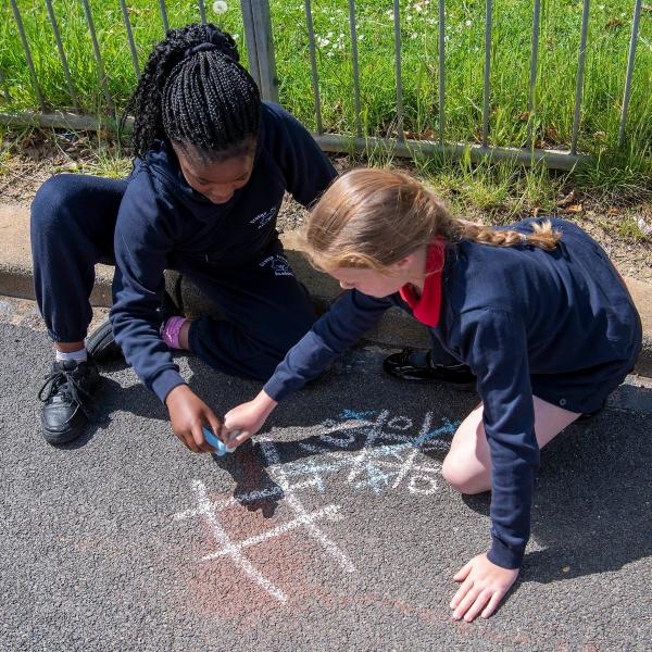 Girls drawing with chalk on the road.